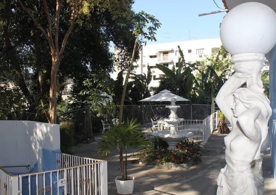 Jardim com fonte e escultura entre árvores