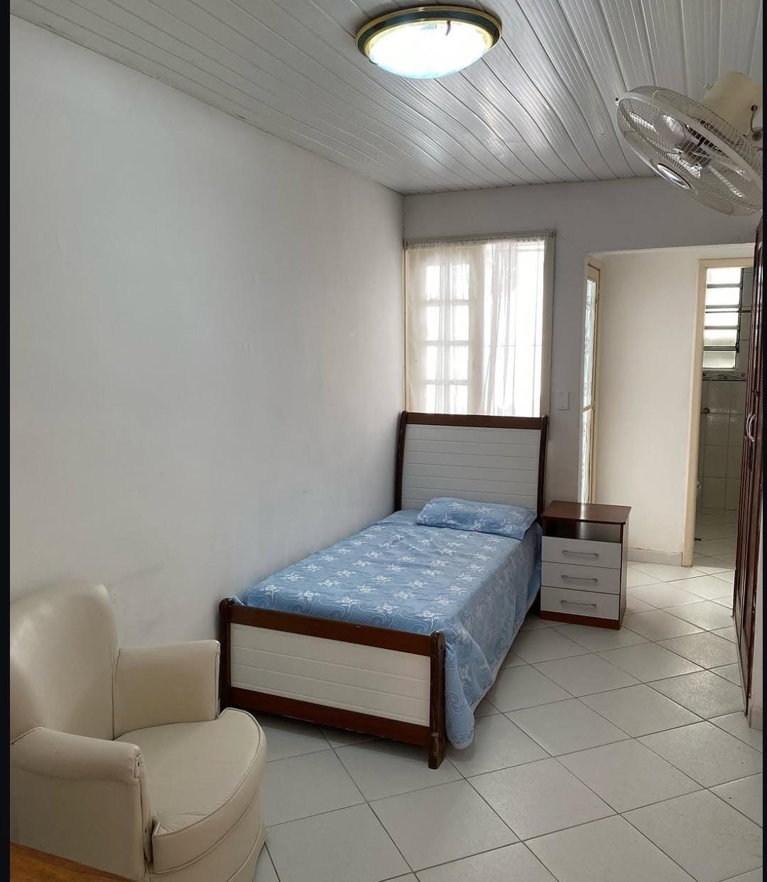 Quarto claro e ventilado com cama e poltrona